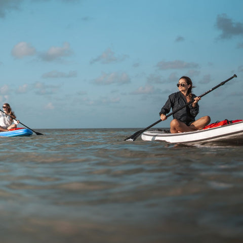 Woman sitting on a paddle board.