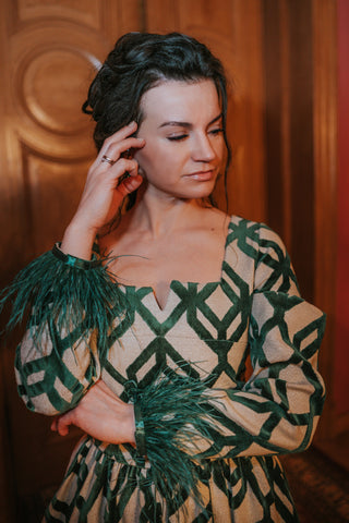 lady in a top with removable sleeves. graceful, dark green colourd outfit. feathers at the end of the sleeves