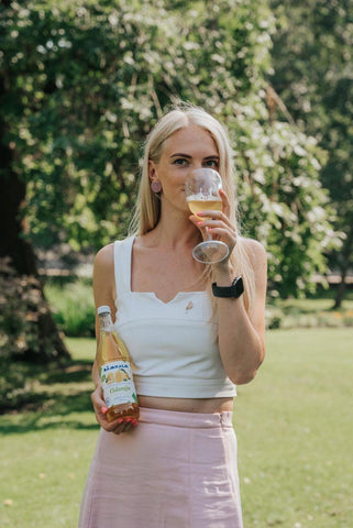 beautiful blond lady in a white top sipping white wine