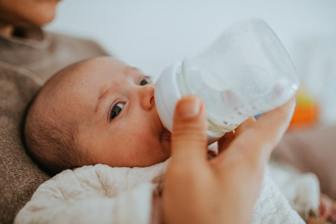 Main Proche De La Mère Tenant Le Biberon De Lait Nouveau-né Bébé Allongé  Sur Le Lit Boire Du Lait à L'endroit Chaud. Lait Pour Béb Image stock -  Image du confort, chéri