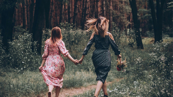 Zwei Frauen laufen Hand in Hand durch den Wald