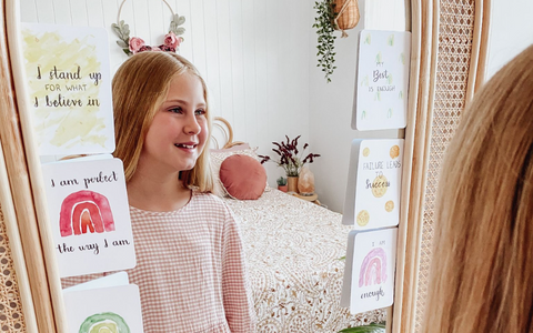 young girl looking in the mirror with affirmation cards for kids 
