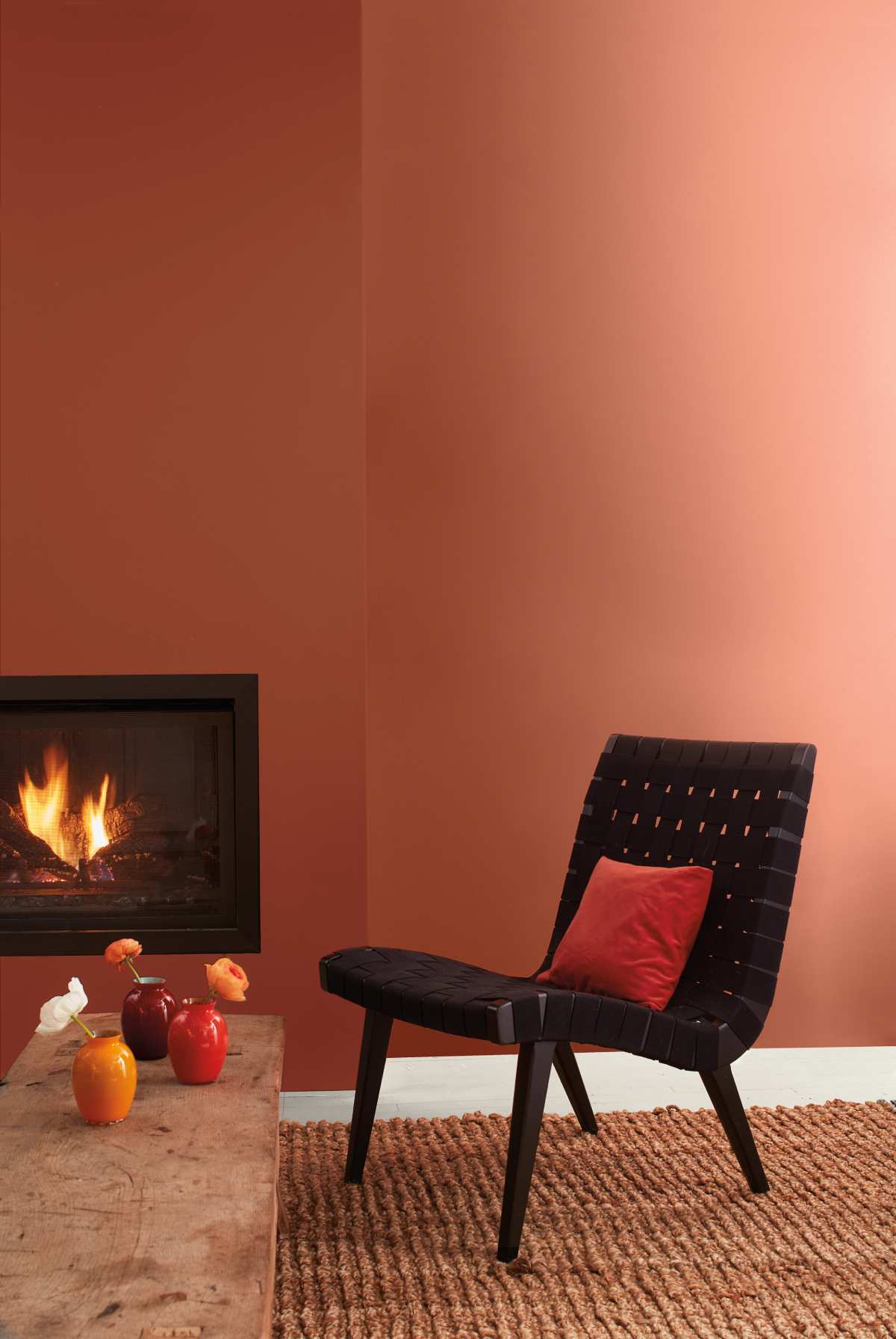 A chair in front of a low table near a burning fireplace