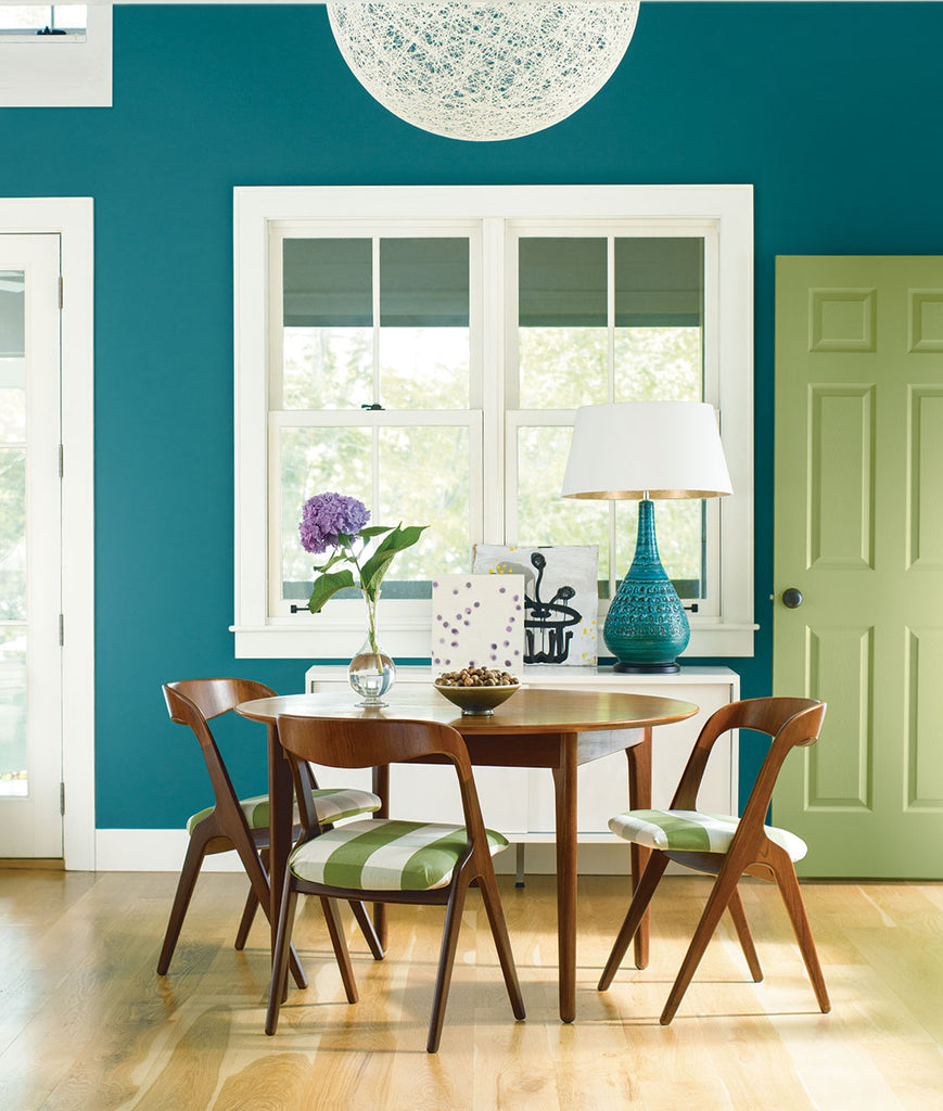 a round wood table with 3 chairs in a room with teal ocean coloured walls