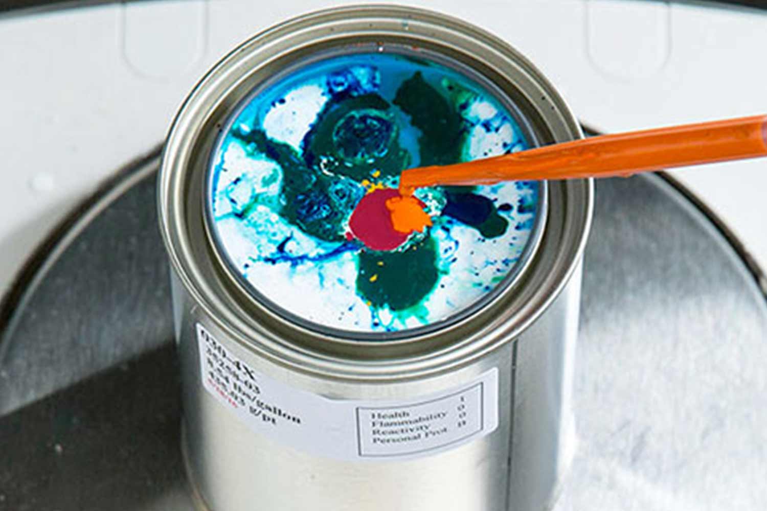 closeup of a paint can with paint being mixed in it