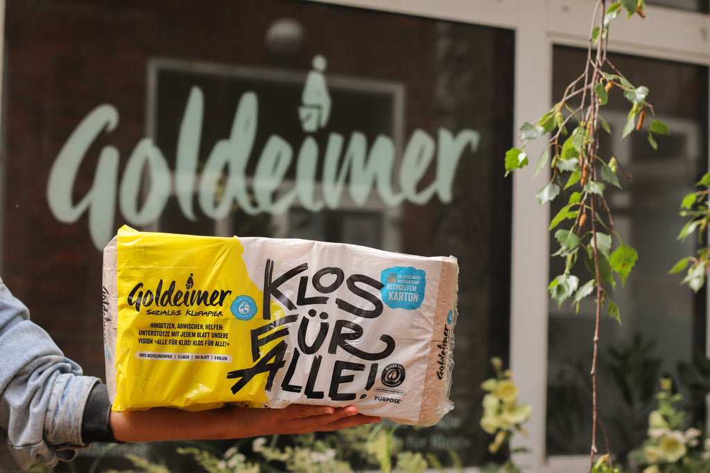 Goldeimer Klopapierverpackung vor Goldeimer Logo