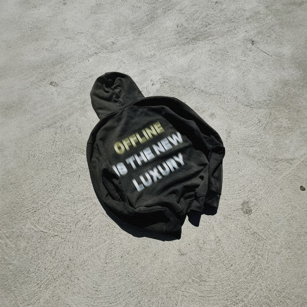 Crumpled black hoodie with 'OFFLINE IS THE NEW LUXURY' text on grey background.