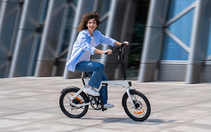 a woman rides a white engwe p20 fold up electric bike