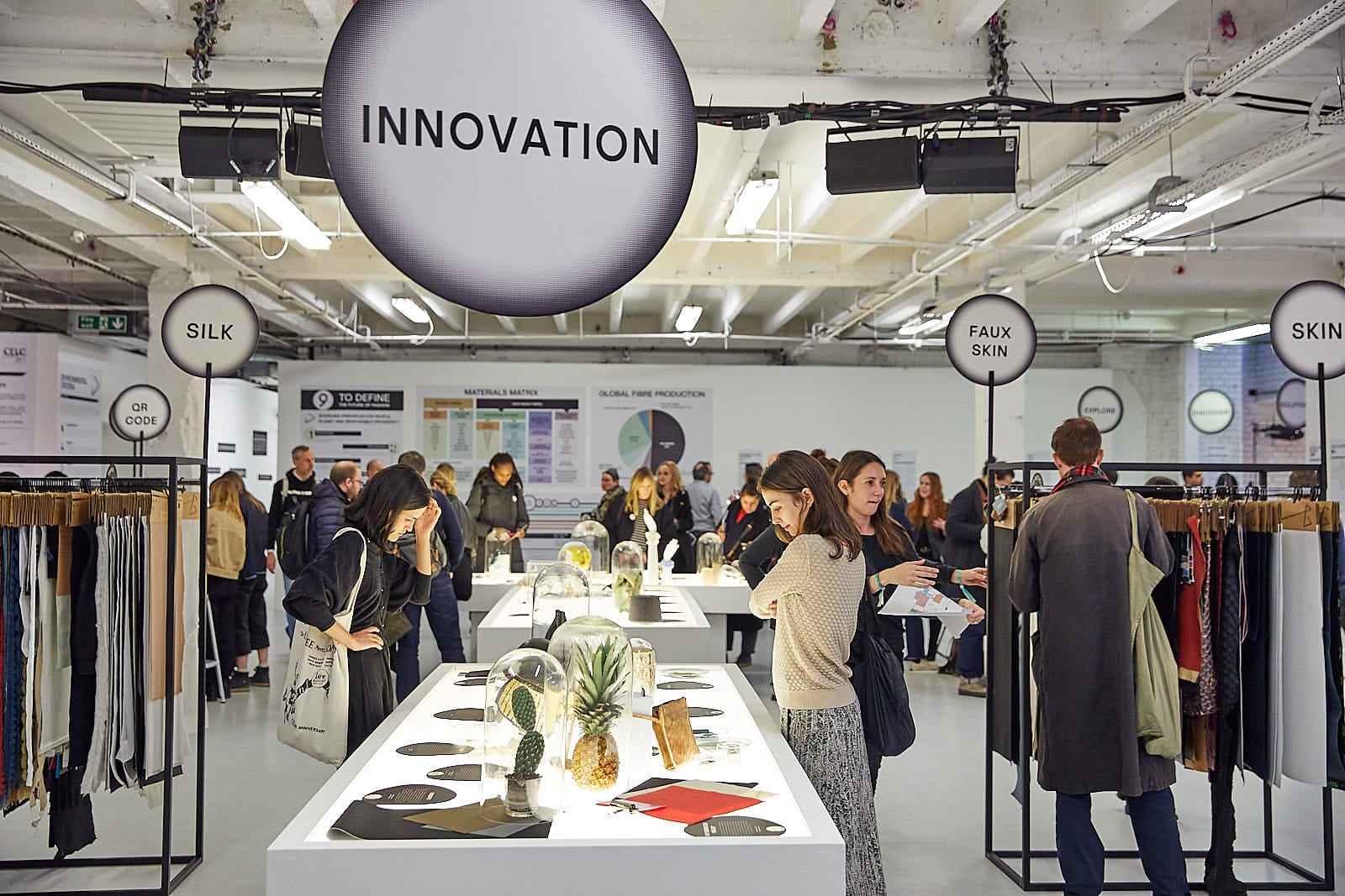 Photo showing a sustainable fashion innovation exhibition with people looking at different stalls