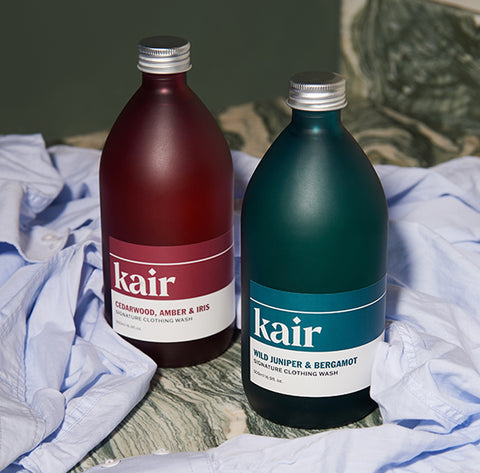 Kair Signature Clothing Wash - Wild Juniper & Bergamot and Cedarwood, Amber & Iris next to a blue shirt