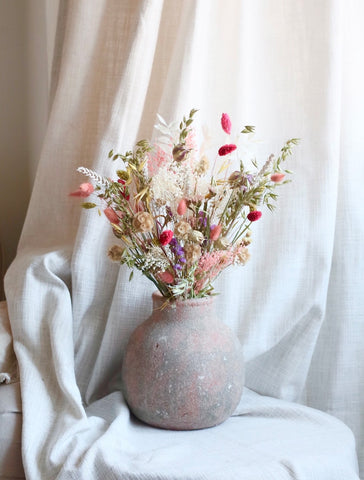 spring dried flower bouquet, full of delicate pastel dried flowers, in a rustic vase set in a neutral living room