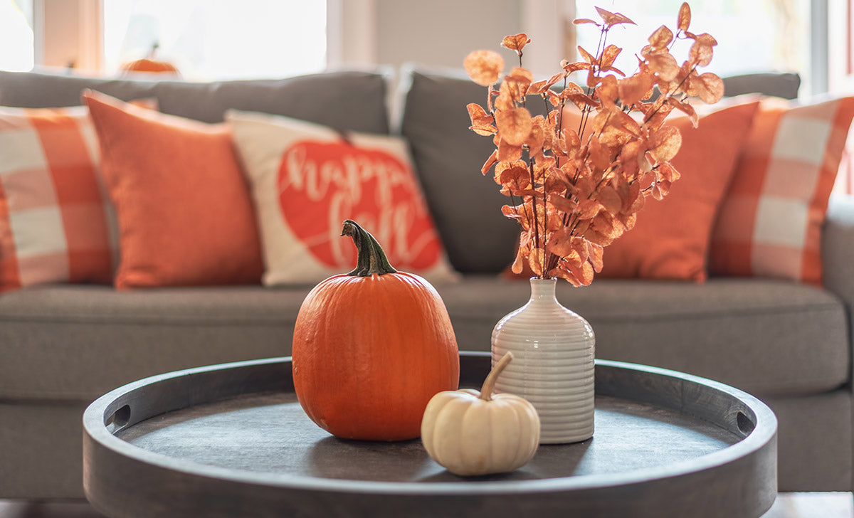 A coffee table and couch decorated with orange accents for fall. 