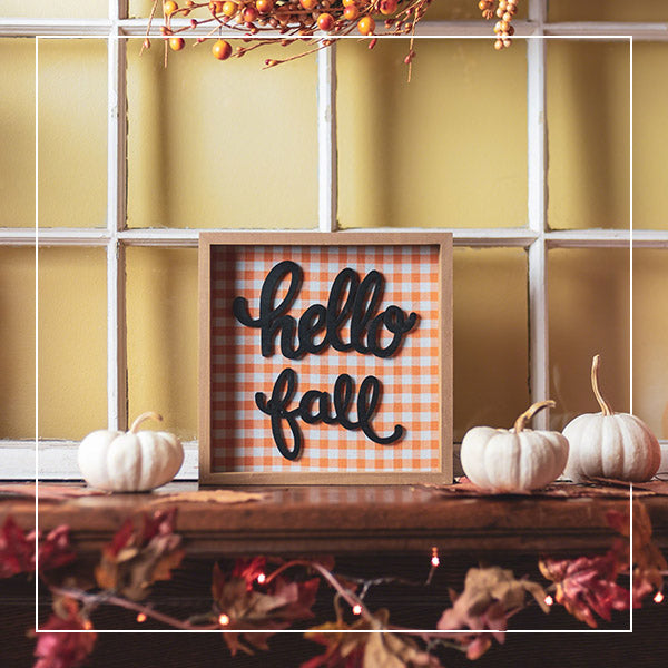 Fall decor on a mantle with the sign “Hello Fall.” 