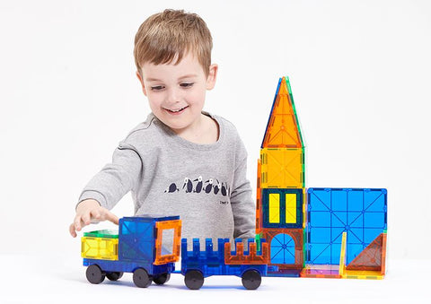 A boy is happy with magnetic shapes building tiles