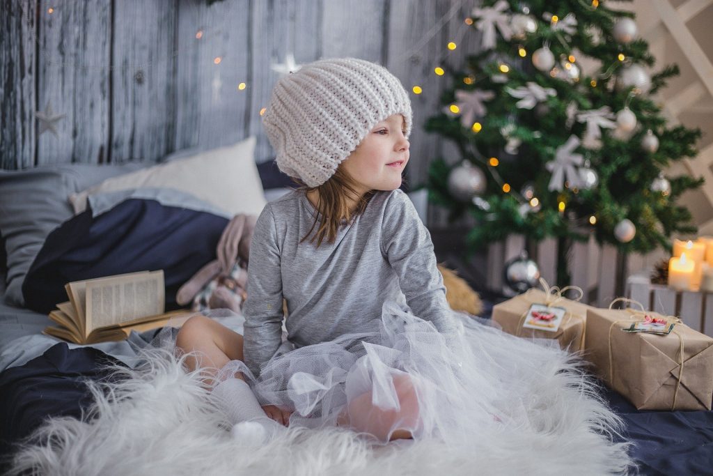 A girl sits in the middle of Christmas gifts