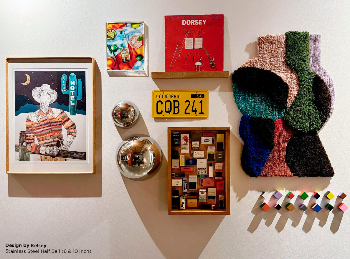 Eclectic collection of wall art including a painting of a cowboy, a multicolored textile piece, and two silver half orbs.