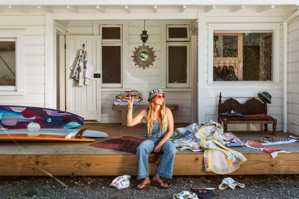 surfer chick giving a peace sign in front of her surf bungalow by the sea