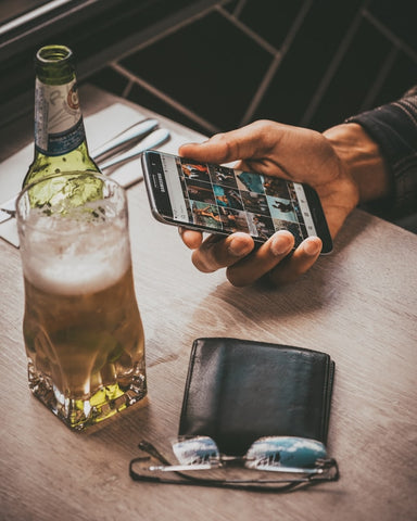 Photograph of an old used leather wallet with a bottle of beer - The Bicyclist