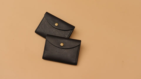 A pair of Card wallet with flap from The Bicyclist in Black full grain leather and a metal snap button