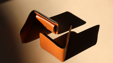 Pair of Ocher Leather Bifold Leather Wallets from The Bicyclist with coin pouch kept standing next to each other