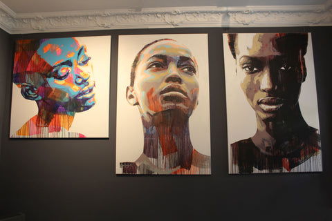 Eine Wand in der Galerie SOUL OF AFRIKA in München, darauf zu sehen sind 3 Kunstwerke von Sarah Danes Jarrett