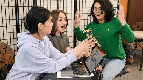 three students playing with Bittle robotics dog kit