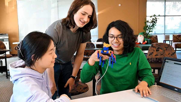 three high school students playing with Bittle X robot dog