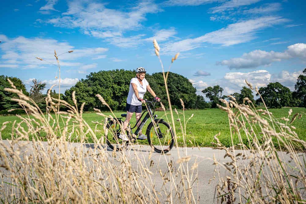 Eine Frau fährt mit dem Wayfarer-Elektrofahrrad auf der Straße