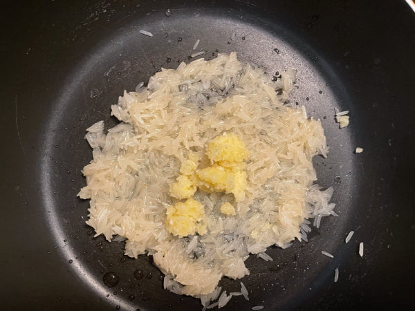 The rinsed rice and minced garlic in a large pot - Serendip Delights Kola Kanda (Herbal Rice Porridge) Recipe Step 1