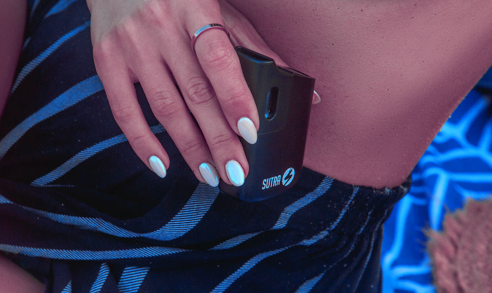 Woman holding Sutra Mini on a beach blanket