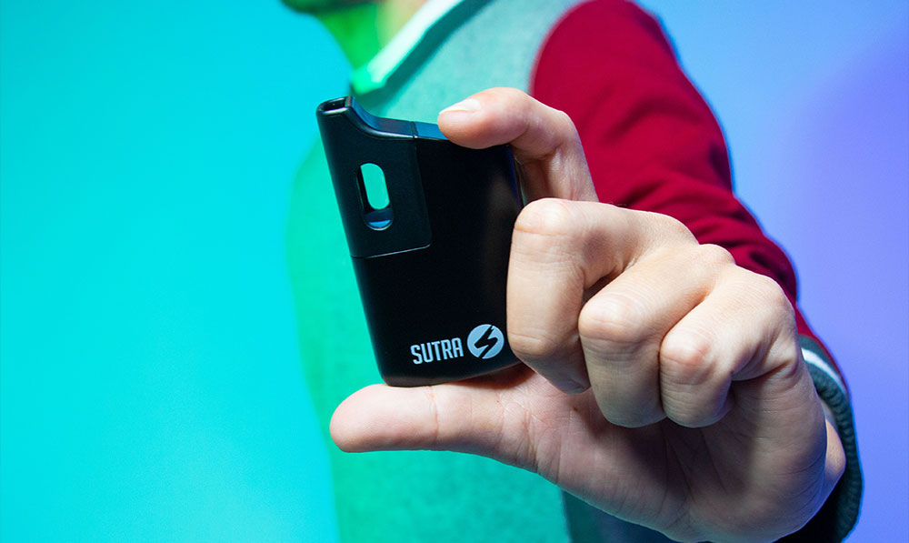 man holding Sutra Mini vaporizer with blue background