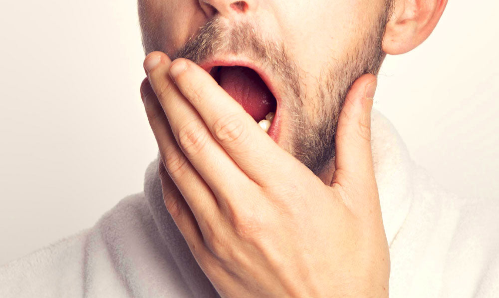 Man yawning in front of light yellow background