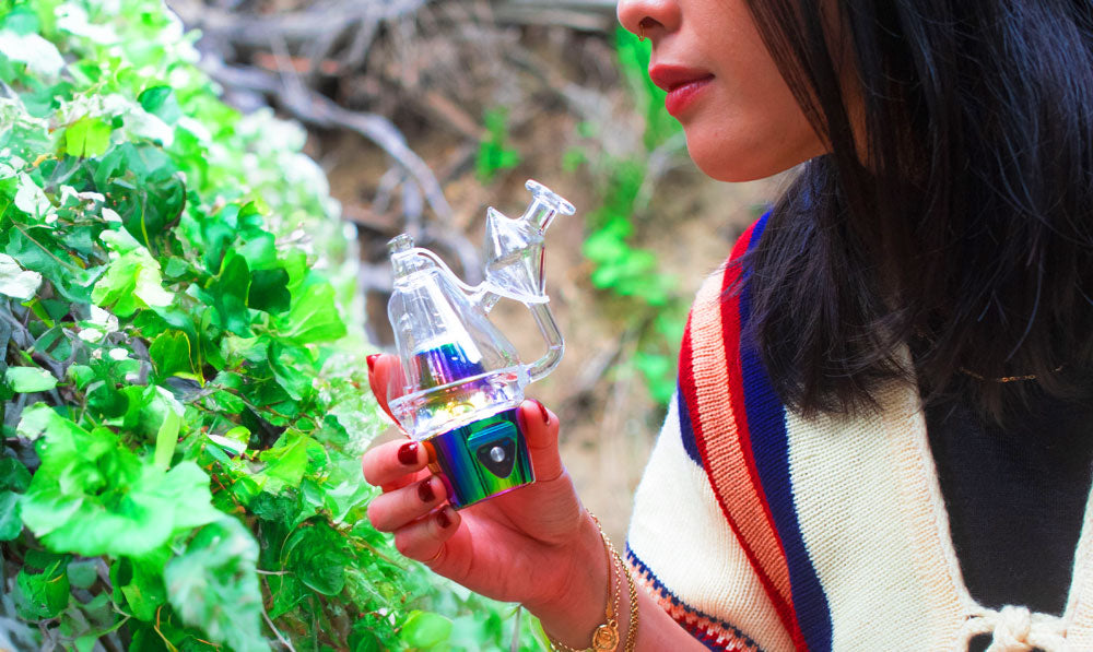 Woman holding Sutra DBR Pro by a creek with luscious plants nearby