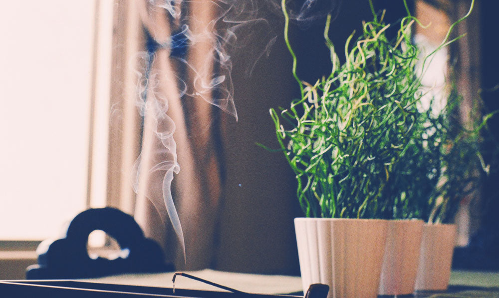 Burning incense stick in front of window with natural sunlight pouring in