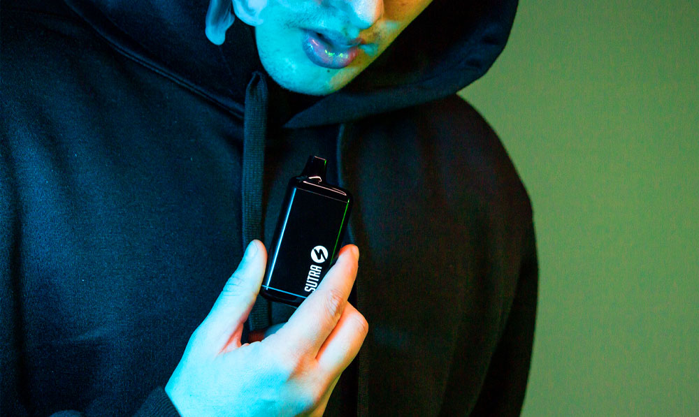 Man vaping with Sutra SILO Pro in front of green studio background