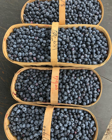 A wooden basket of freshly picked blueberries