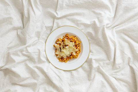 plate of spaghetti on bed