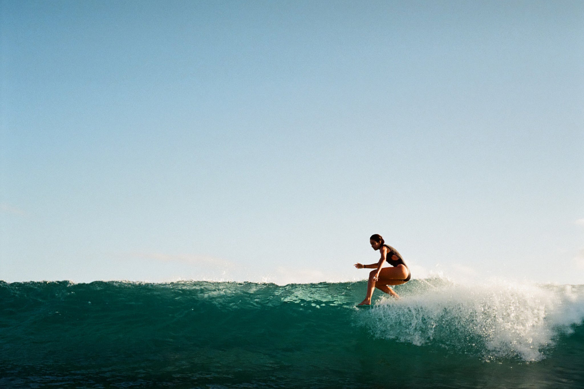 women surfing a perfect wave in black one piece swimsuit