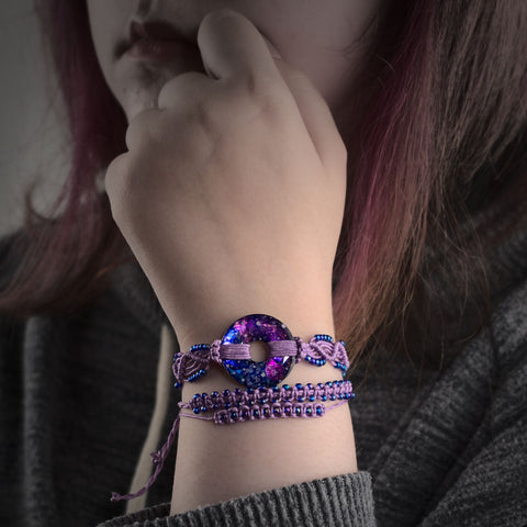 Young woman with a stack macramé bracelet featuring a hand painted galaxy doughnut shaped pendant