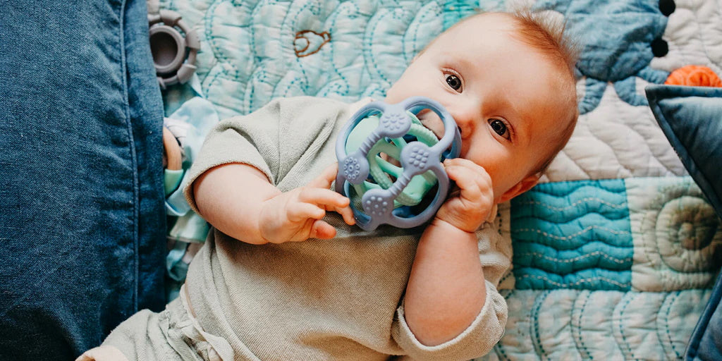 Baby with a blue Sensory Ball teething toy from Jellystone. Belly Beyond.