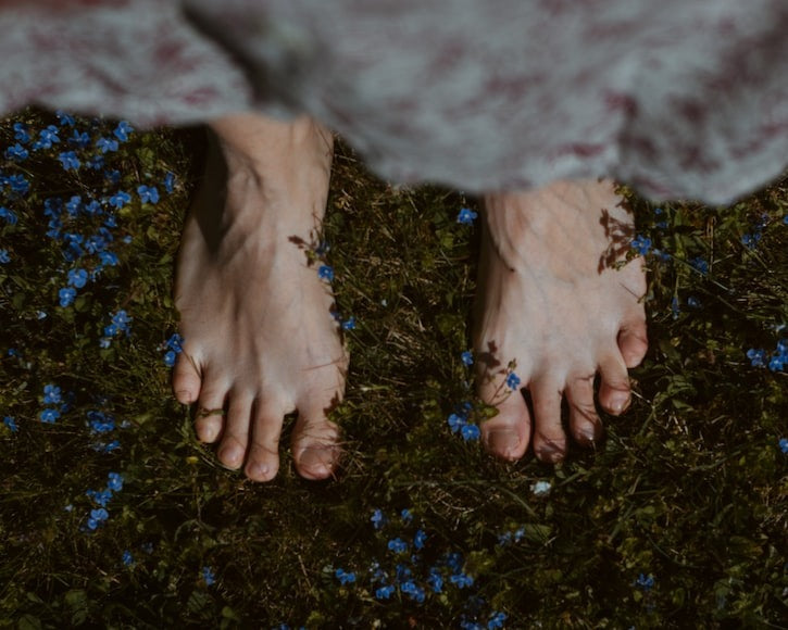 barefoot person on top of flowery grass
