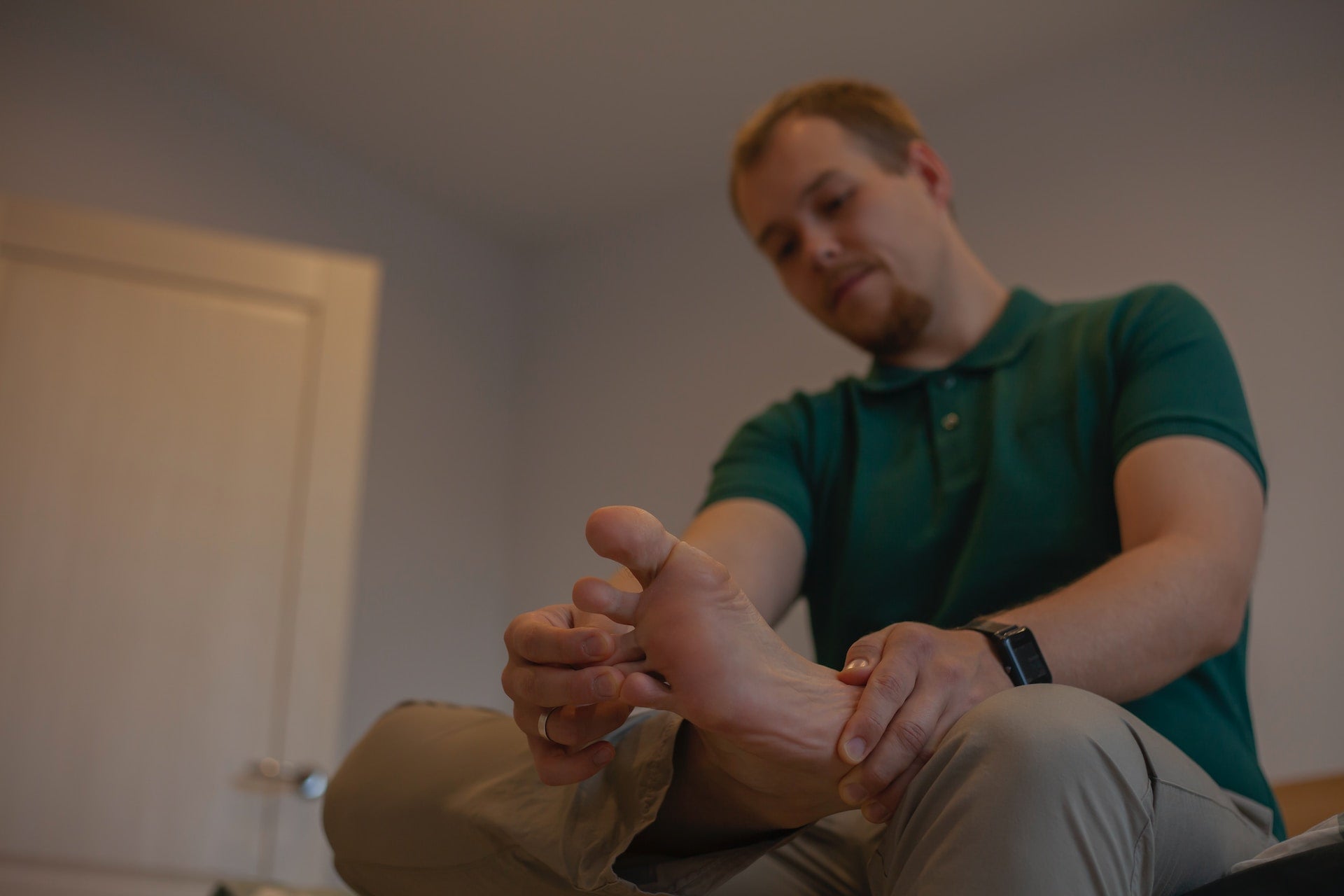 man sitting on a bed with aching feet
