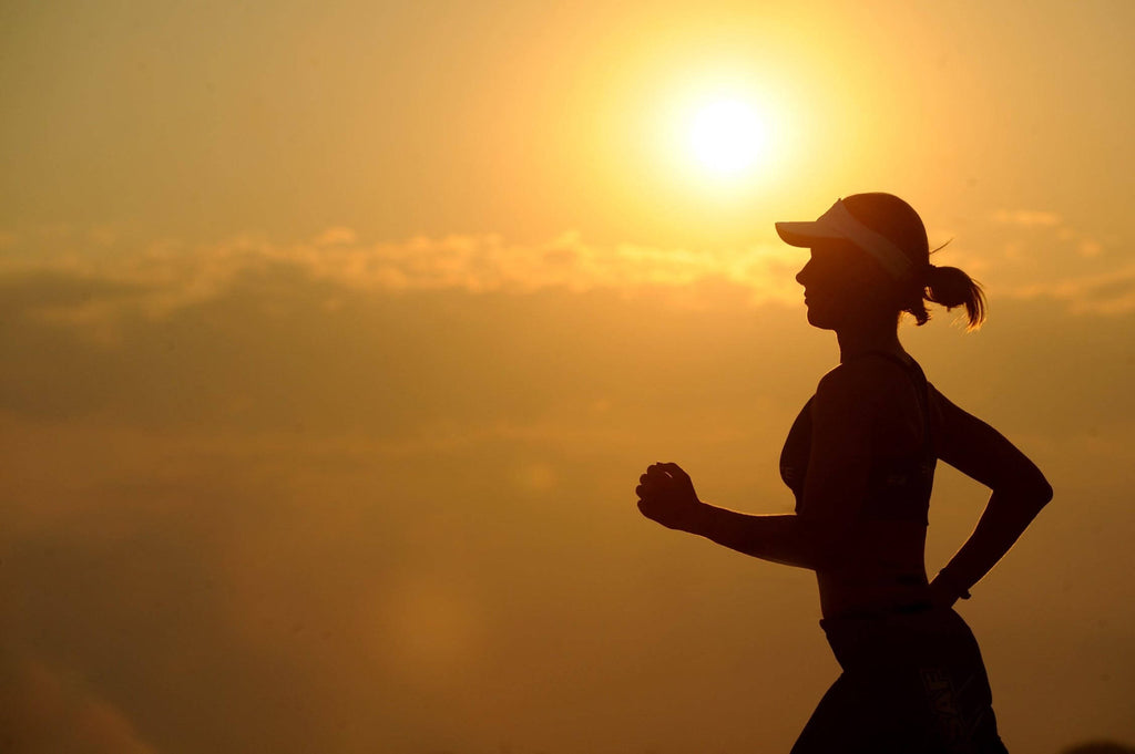 Woman wearing running toe socks running with the sun in the background