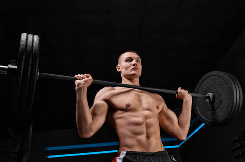 Muscular man holding a weighted barbell under his chin.