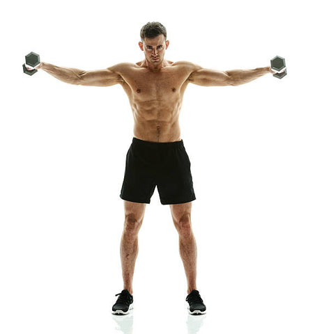 Muscular man in black shorts and running shoes with his arms stretched out to the sides and a dumbbell in each hand.