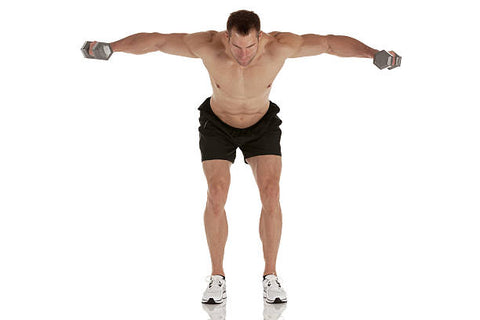 Muscular man in black shorts and white running shoes bent over with arms extended up and out at shoulder height holding a dumbbell in each hand.