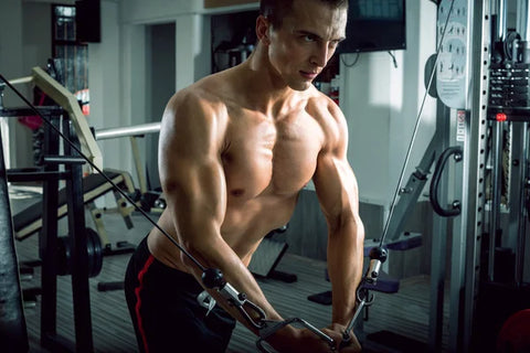 Muscular man leaning forward into the end position of a high to low cable fly.