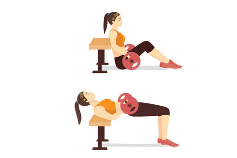 A set of two illustrations of a woman performing an inclined hip thrust against a weight bench with a barbell across her lap. The first image is of the start position seated on the ground and the second of the top of the motion with her body flat through the knees.