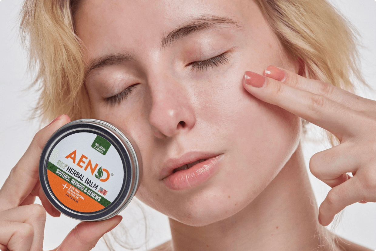 A woman uses AenoAcne balm on her face 