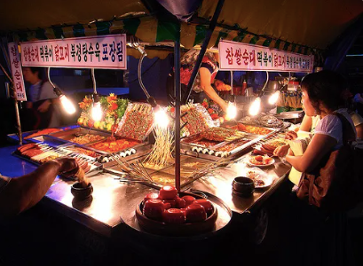A young girl at a food stall selling tteokbokki